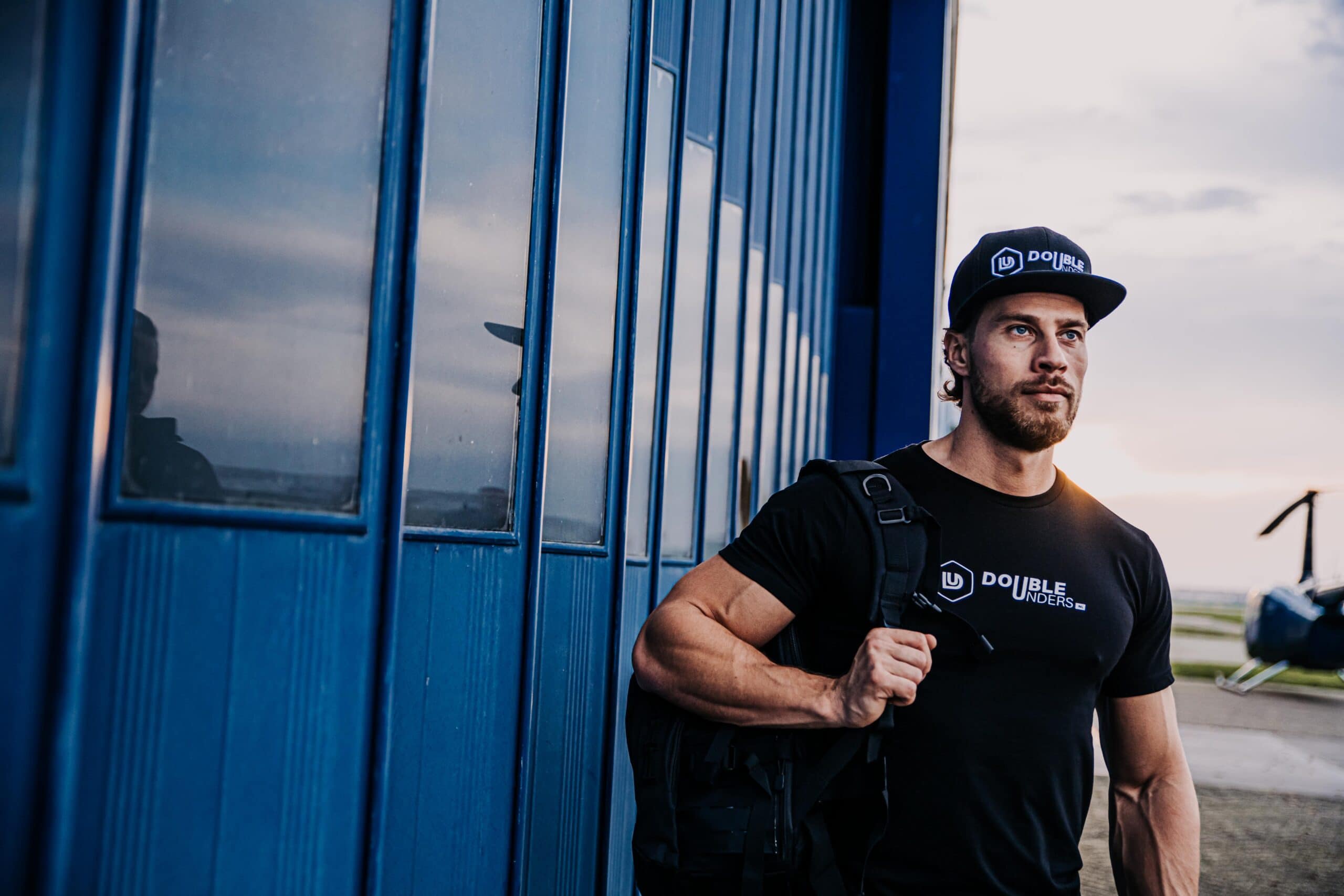doubleunders apparel gedragen door een man die zowel de fitness tas zwart, shirt zwart en snap back zwart