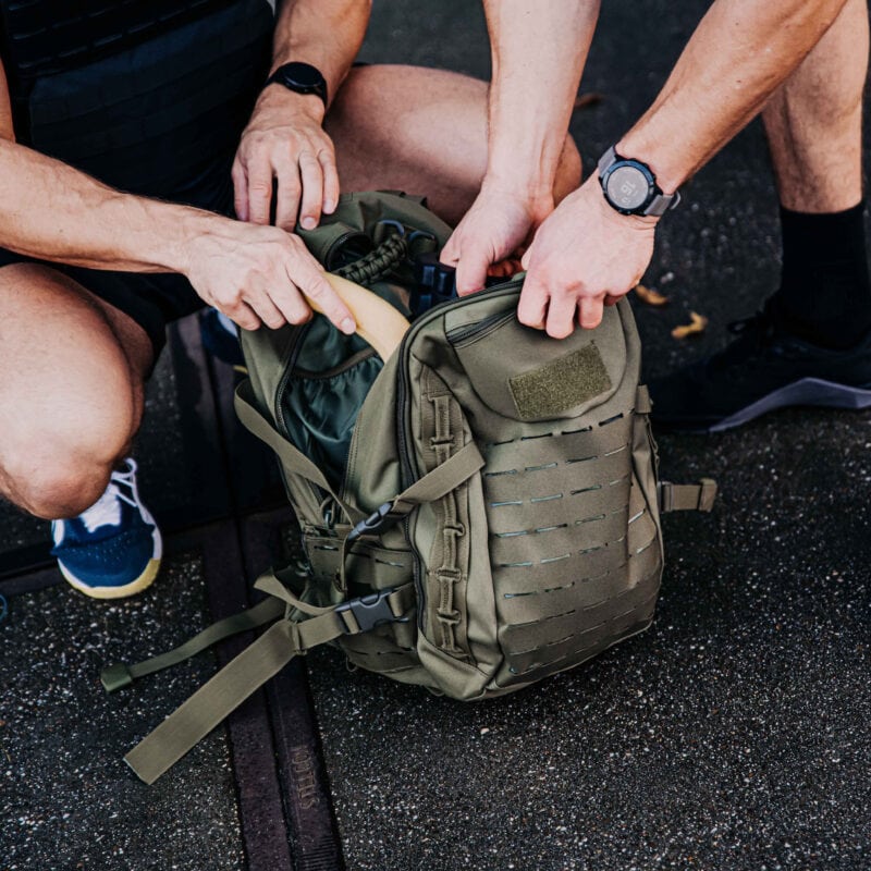 fitness tas in de kleur groen waarbij twee crossfit atleten materialen uit het middenvak van de tas pakken