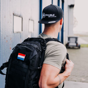 fitness tas zwart met een Nederlandse patch op de achterkant die op de rug wordt gedragen door een man met een doubleunders snapback