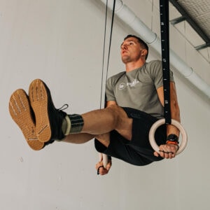 l-sit in houten gym ringen, waarbij een crosstraining atleet in een hoek van 90 graden in de ringen hangt